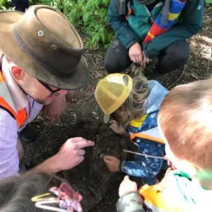 practitioner with earwig on his finger, children looking at bug or searching for more